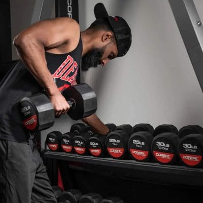 Athlete placing a CoreFX rubber dumbbell onto a commercial weight rack