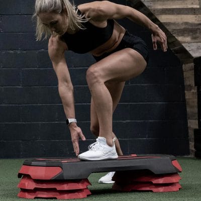 Fitness user performing step aerobic training on adjustable platform