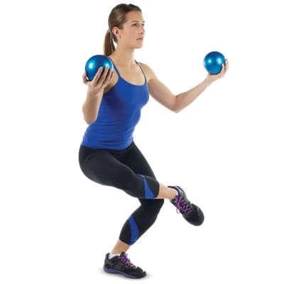 Woman performing balance exercise using two weighted yoga balls during yoga workout