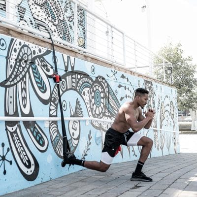 Person doing single-leg squat balance exercise with foot in CoreFX suspension loop