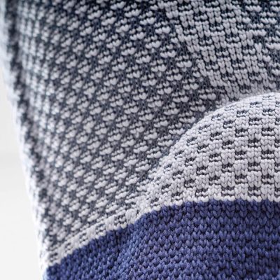 Close-up of the knit material on the titan and blue Bauerfeind GenuTrain P3 knee brace with grip top