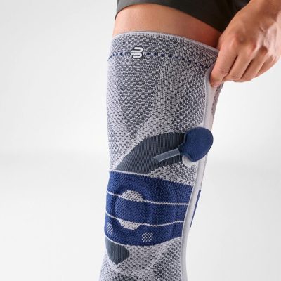 Front view of the titan and blue Bauerfeind GenuTrain P3 knee brace being pulled on the leg